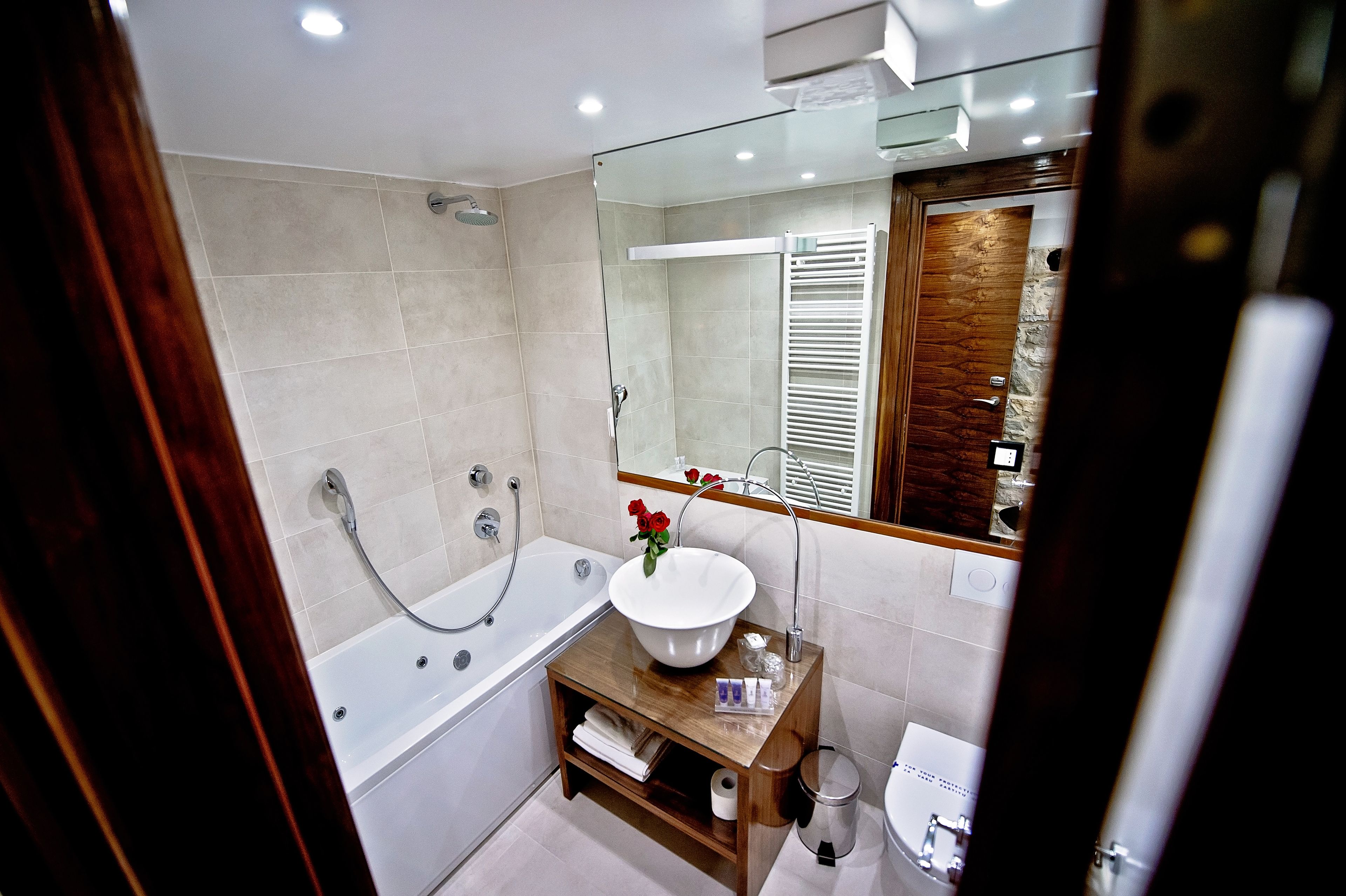 A modern bathroom with a bathtub, a sink with a large basin, and a mirror.