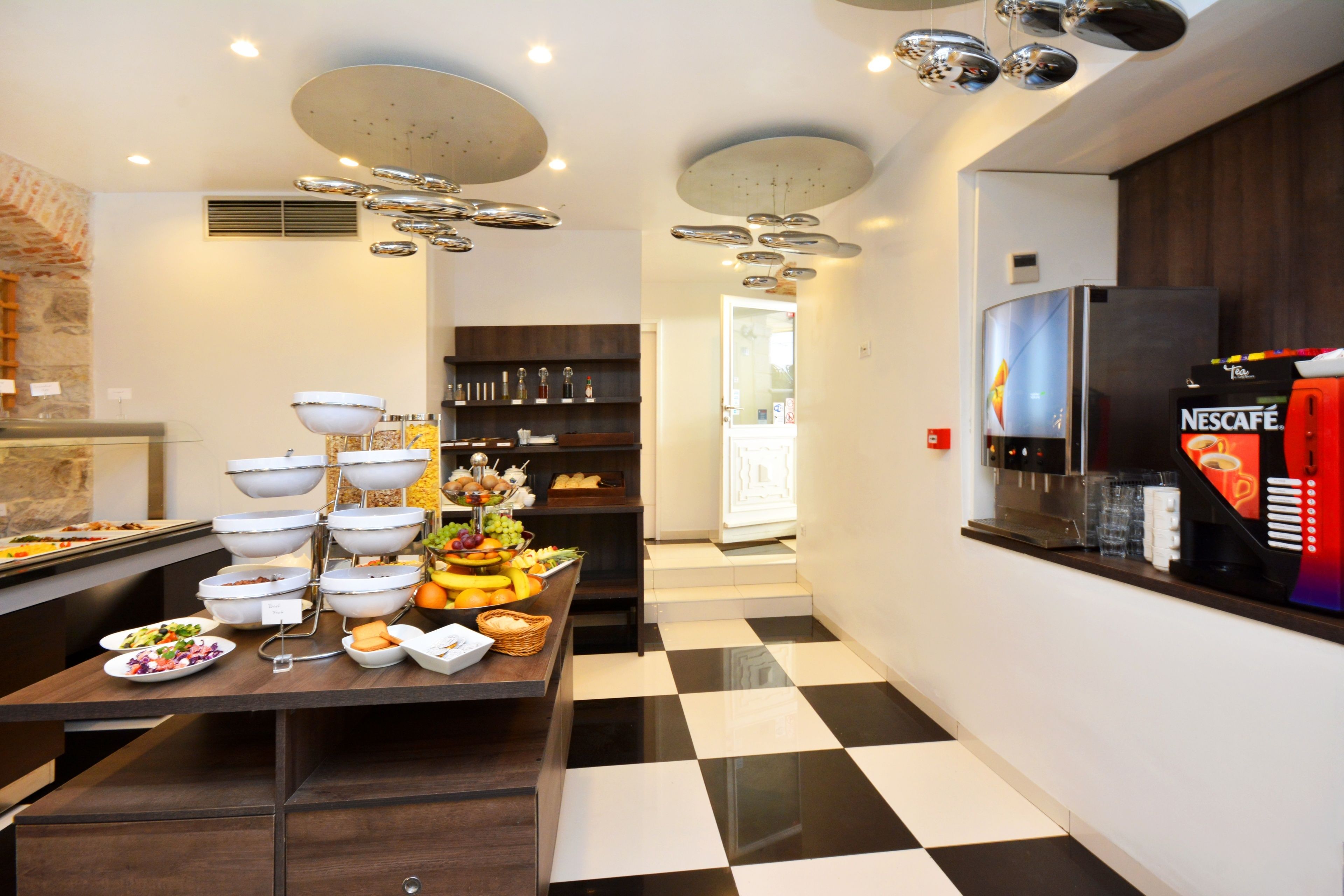 Zona de bufé con diferentes opciones de comida y una máquina de café Nescafé.
