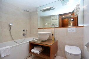 Une salle de bain moderne avec un meuble-lavabo entouré de parois en verre, une baignoire sur pieds et des toilettes.