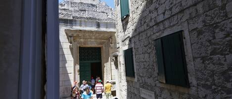 A narrow street with stone buildings, a dome structure, and a sign reading "RAJ. S. DANA".