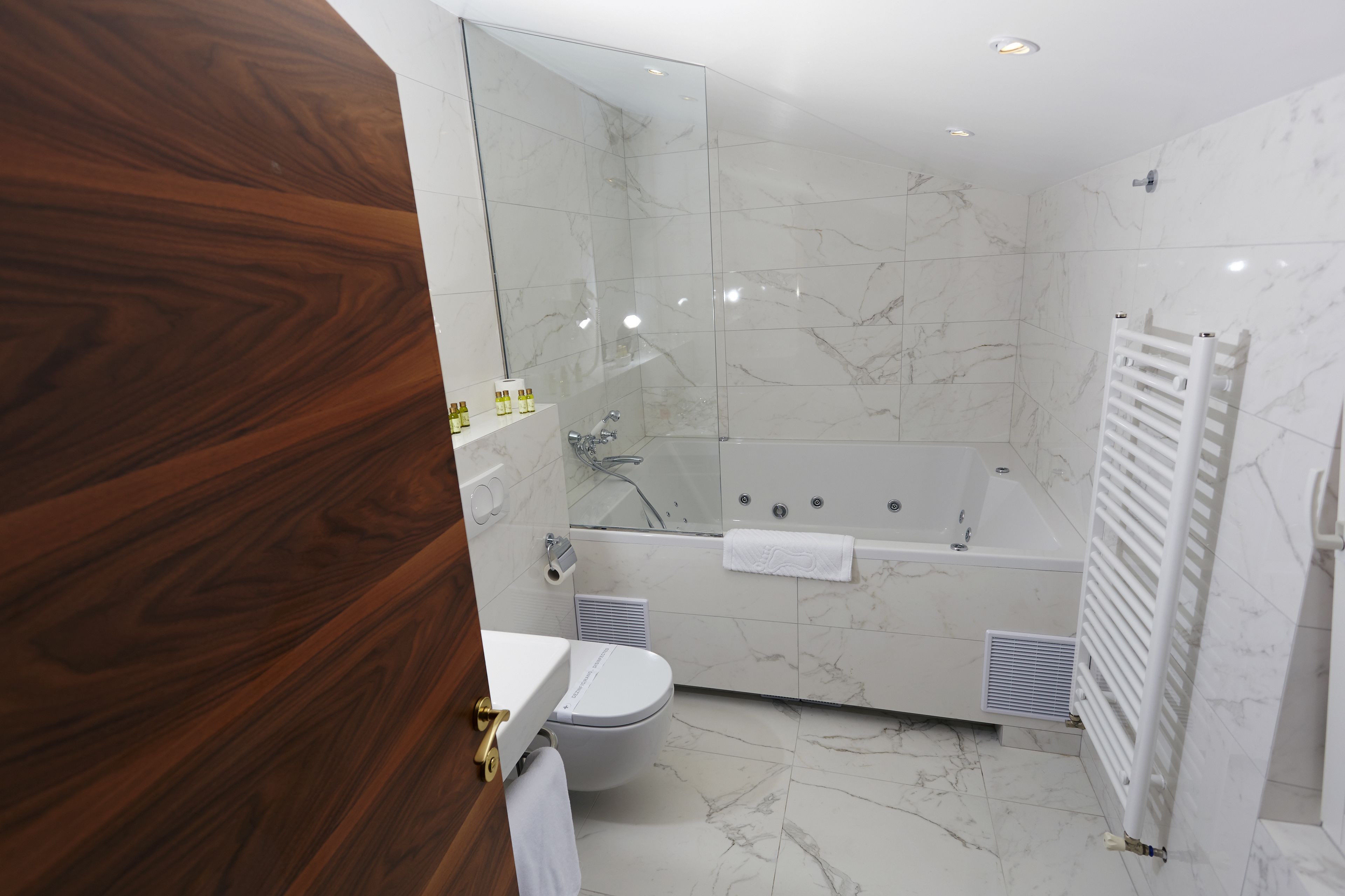 A modern bathroom with a glass-enclosed shower, a white bathtub, and a toilet.