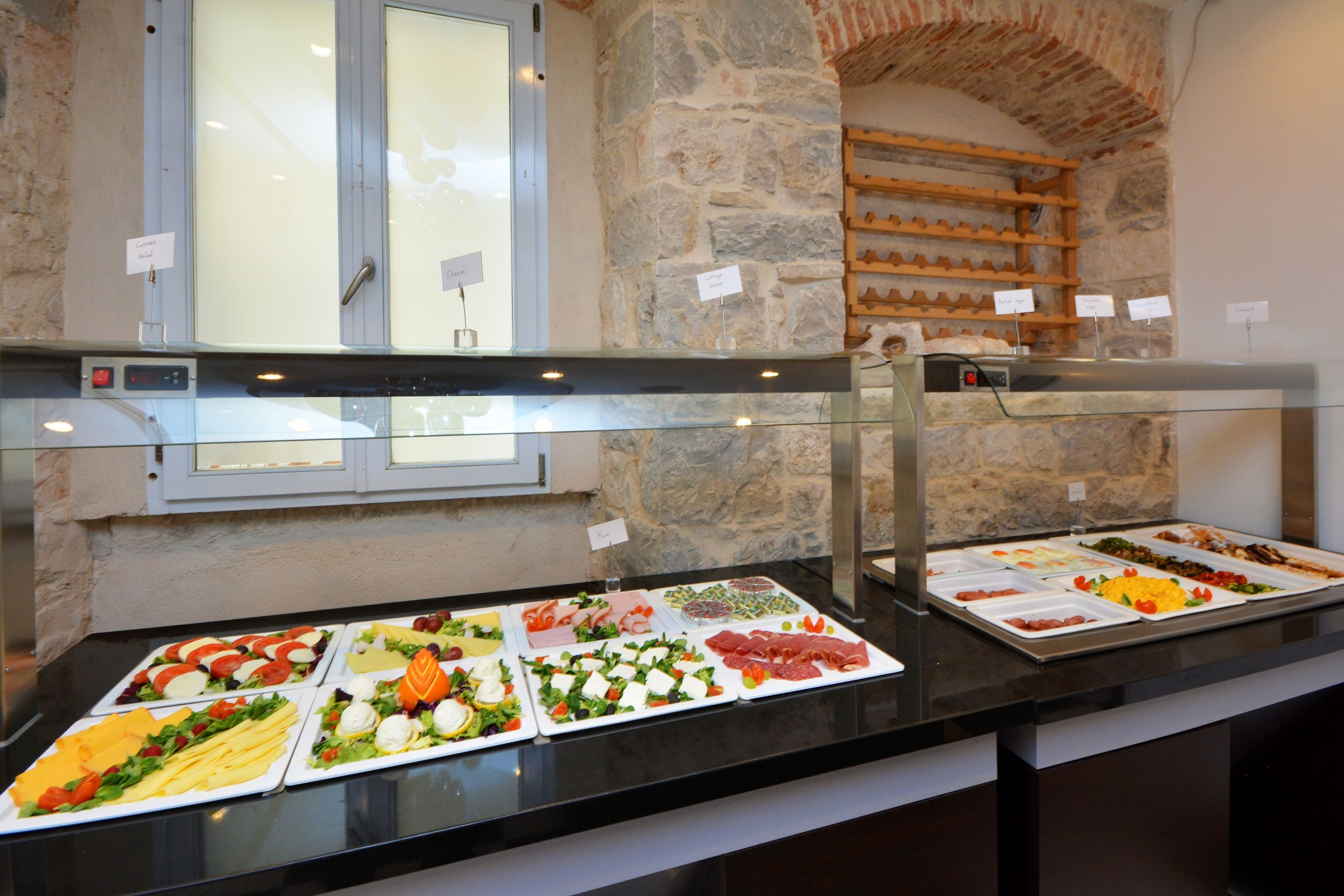 Un buffet proposant une variété de plats, un mur en pierre et une fenêtre avec du verre dépoli.