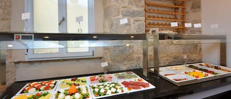Un buffet proposant une variété de plats, un mur en pierre et une fenêtre avec du verre dépoli.