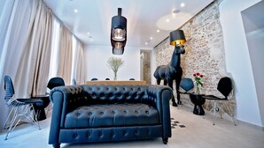 A modern living room with a black leather sofa, a dining table with chairs, and a unique black horse statue. - Heritage Jupiter Luxury Hotel (Split)