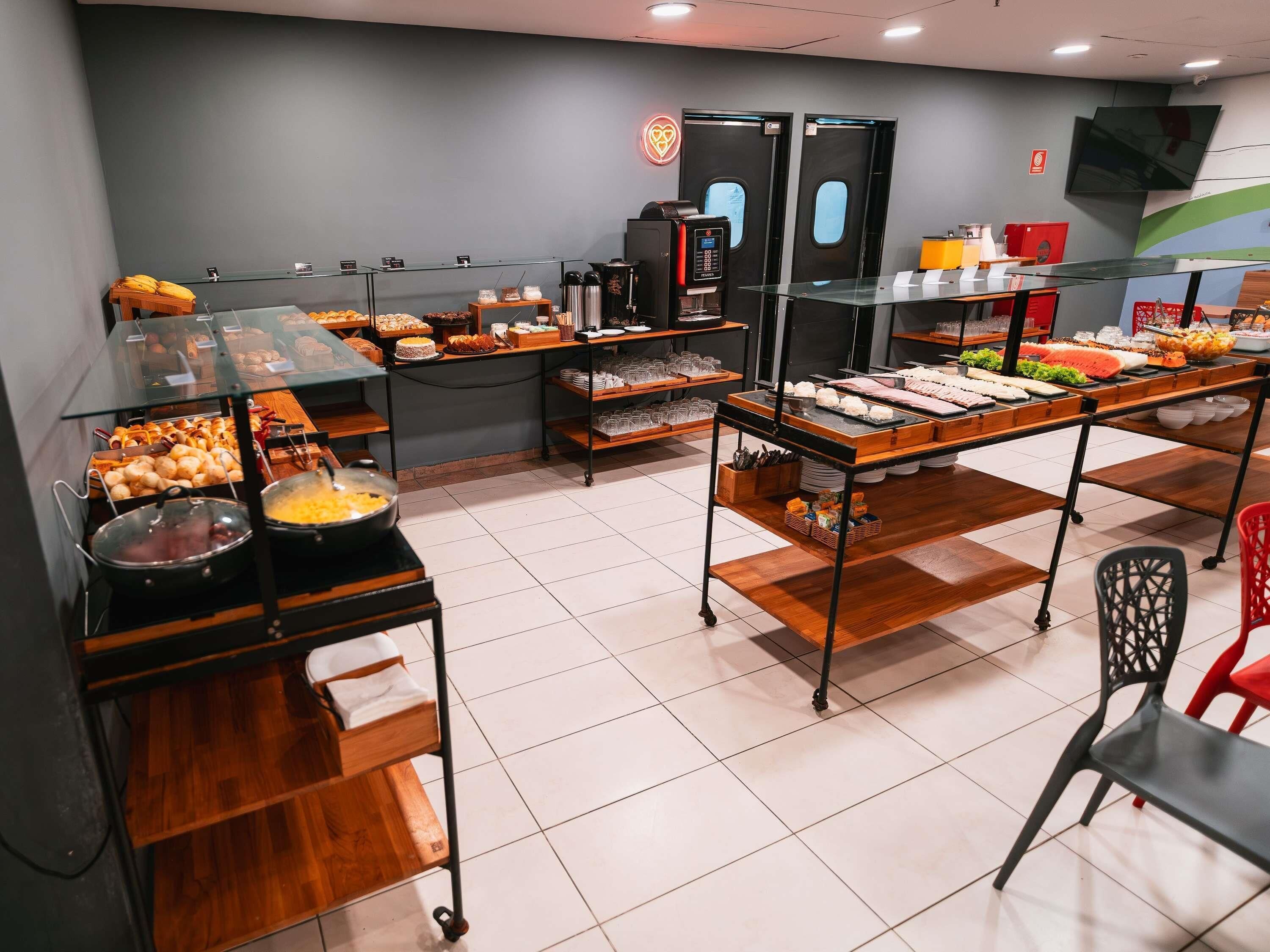 Zona de bufé con diversas opciones de comida, una máquina de café y una sala de estar con sillas.
