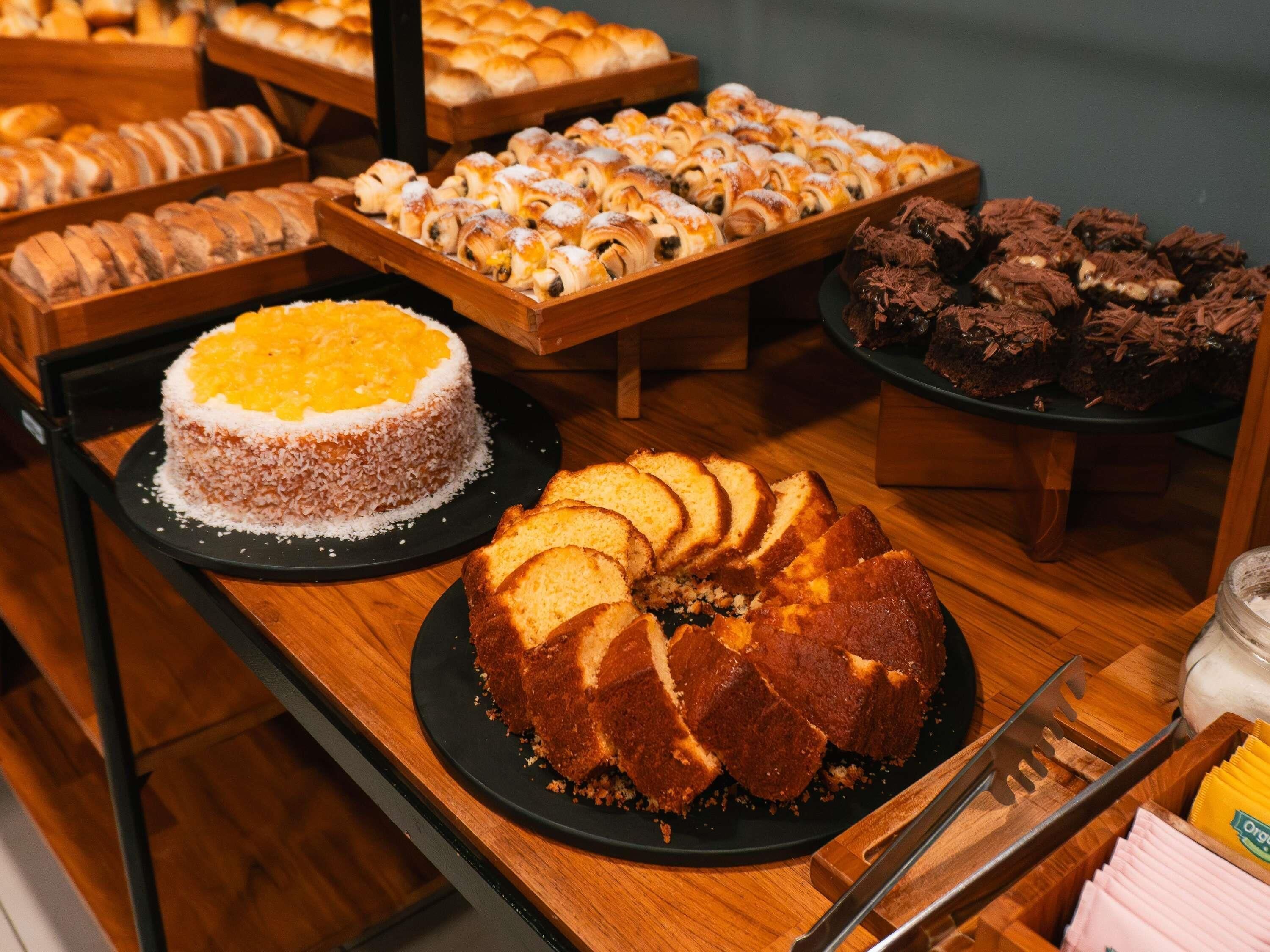 Un bufé con diversas opciones de panadería, incluyendo un pastel, pasteles y un pastel ring.