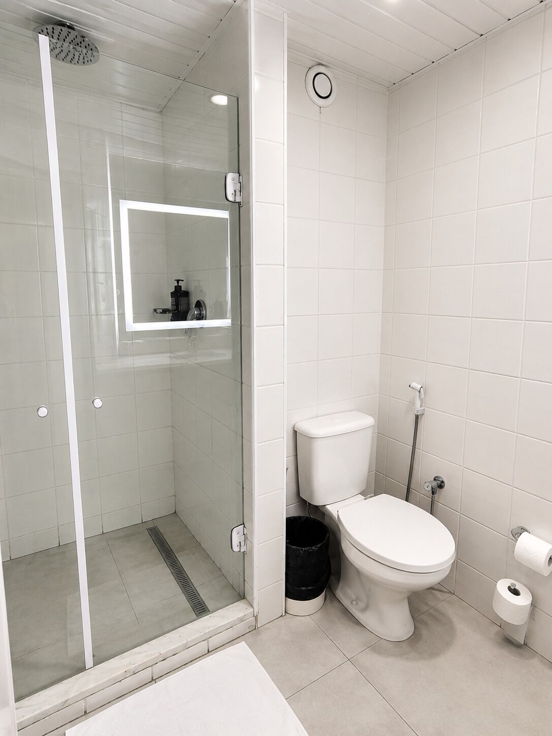 A modern bathroom with a glass-enclosed shower, a toilet, and a sink.