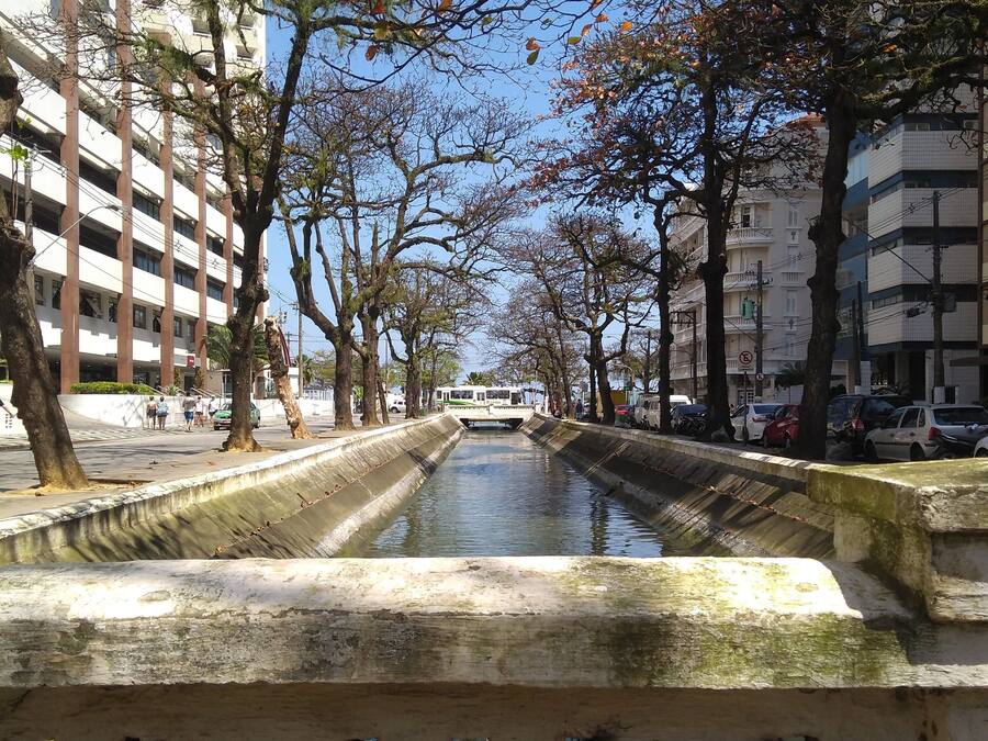 A canal lined with trees and buildings, with a clear sky above.