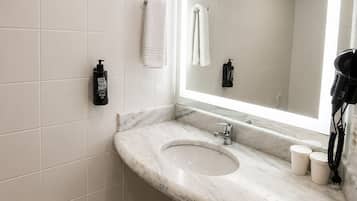 Un bany amb un lavabo de marbre, un mirall gran i dues tovalloles penjades a la paret.