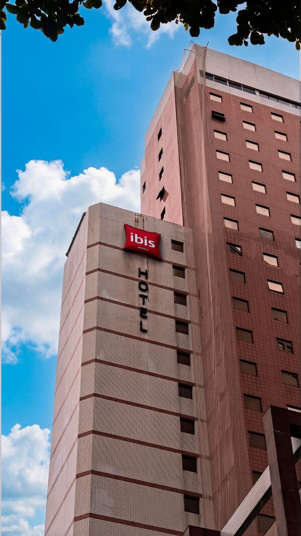 A hotel building with a prominent 'ibis Hotels' sign, multiple windows, and a tiled facade. - Ibis Santos Gonzaga Praia (Santos)