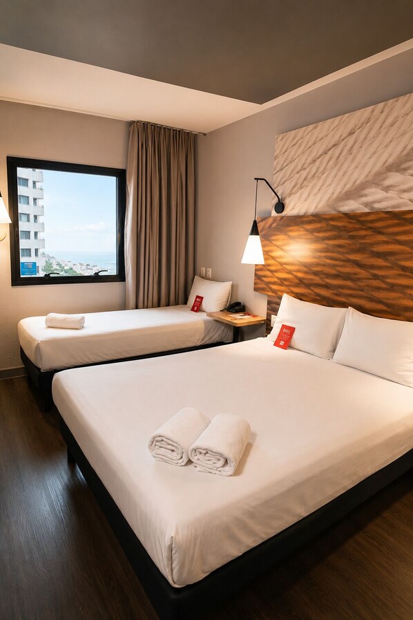 Une chambre d’hôtel avec deux lits, une fenêtre donnant sur un paysage agréable, une lampe et une œuvre d’art accrochée au mur.