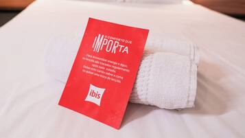 Una cama bien hecha con sábanas blancas y una etiqueta roja con texto.