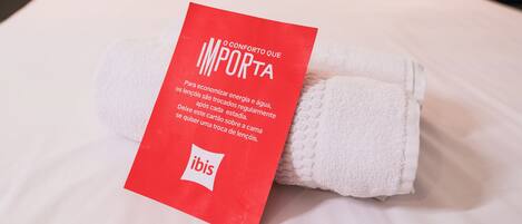 Una cama bien hecha con sábanas blancas y una etiqueta roja con texto.
