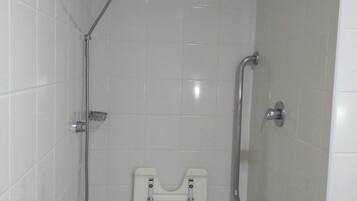 Ducha con barra de apoyo, cabezal de ducha de mano y asiento fijado a la pared.