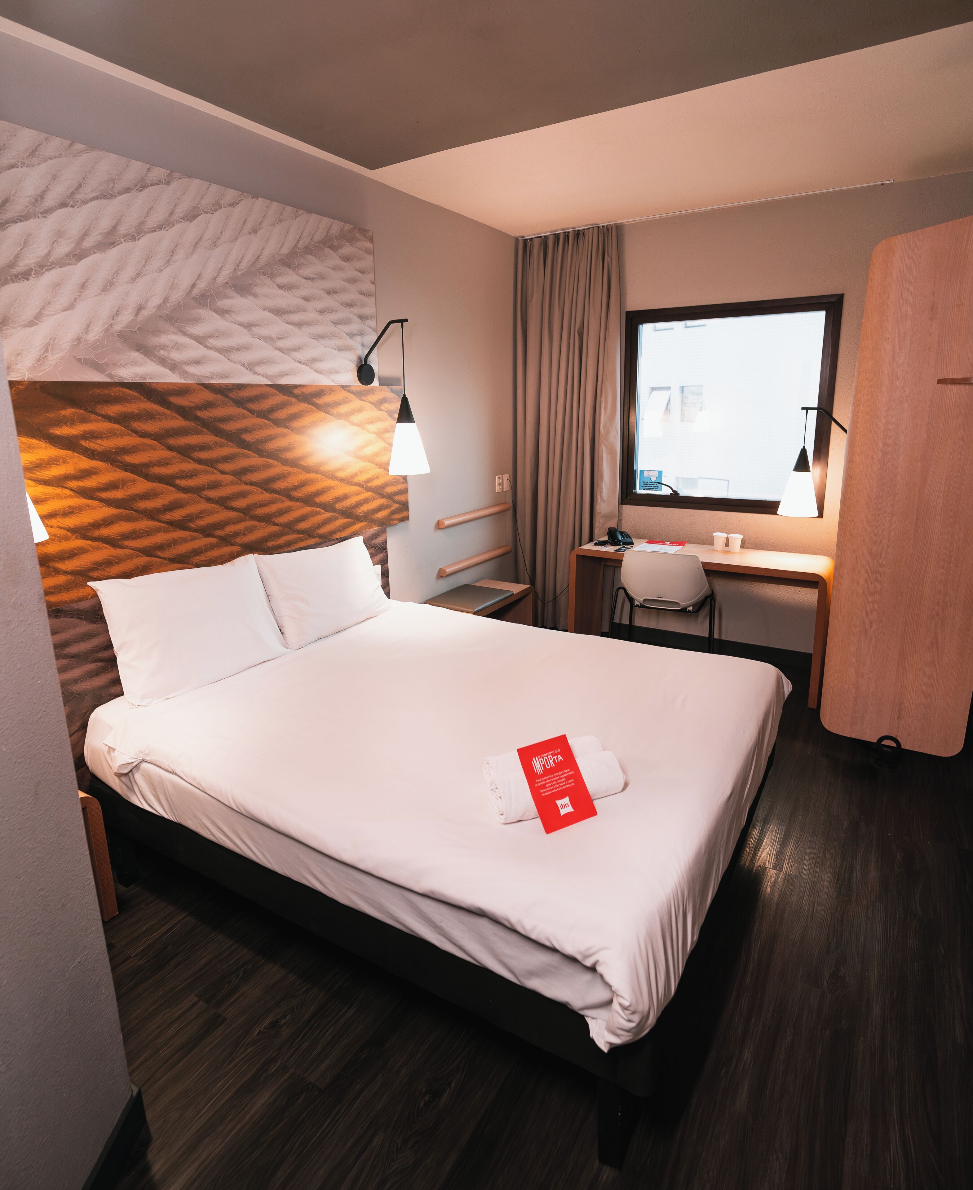 Una habitación de hotel con cama, escritorio y ventana.
