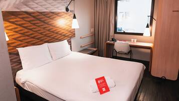 Una habitación de hotel con cama, escritorio y ventana.