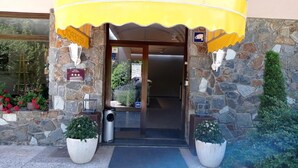 A hotel entrance with a stone facade, a yellow awning, and a sign indicating a 3-star rating. - Sol Park (Sant Julia de Loria)