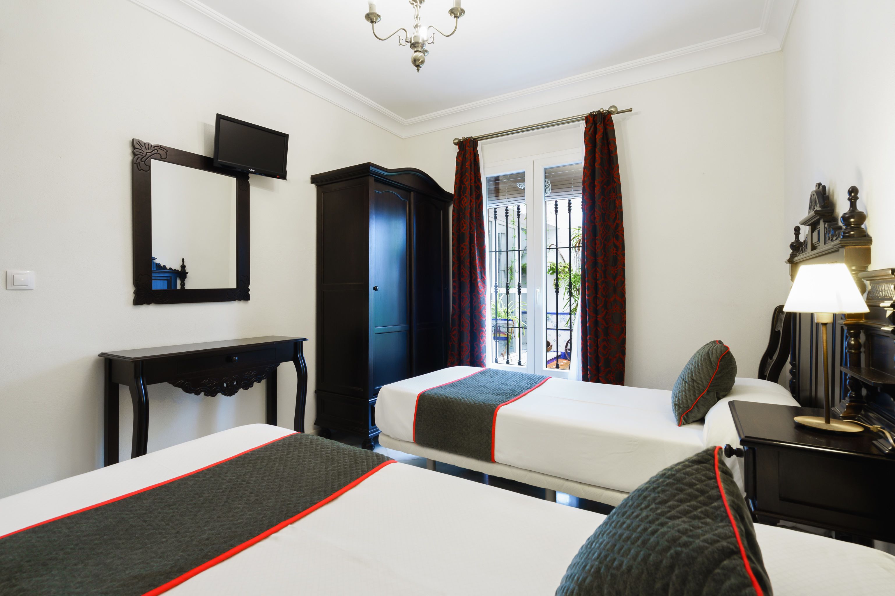 A hotel room with two beds, a TV, a wardrobe, and a lamp.