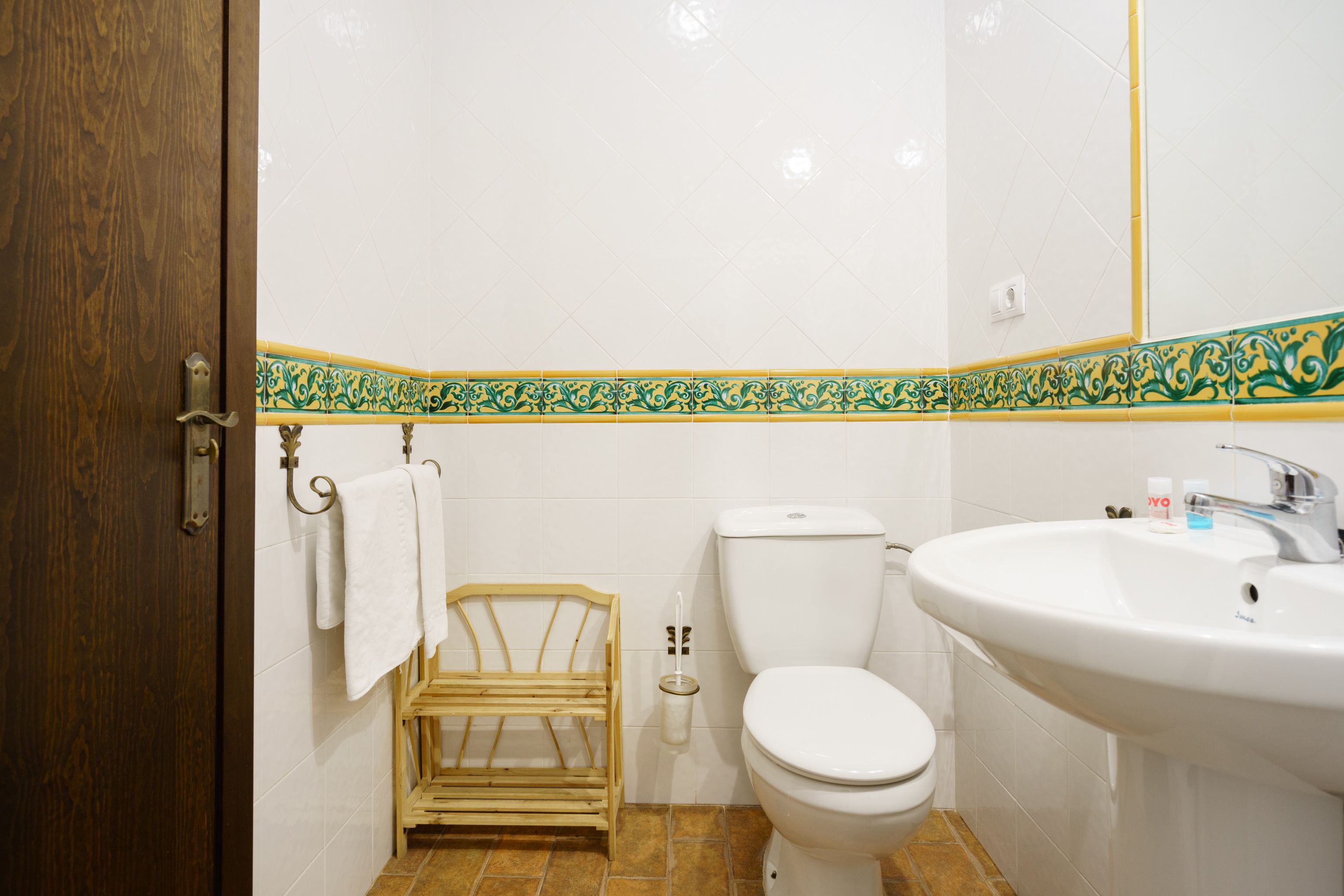 A bathroom with a wooden door, a toilet, a sink, and a towel rack.