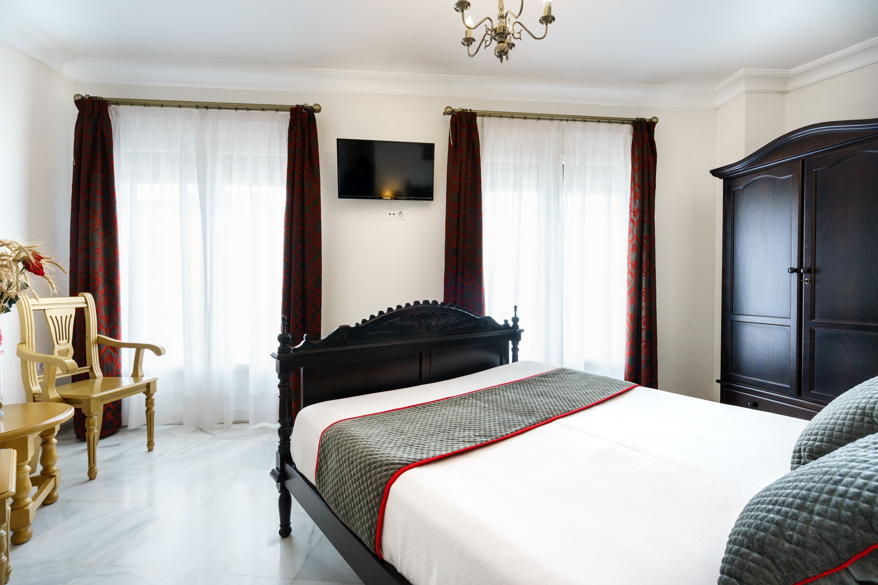 Un dormitorio con cama, televisor, armario y una silla.