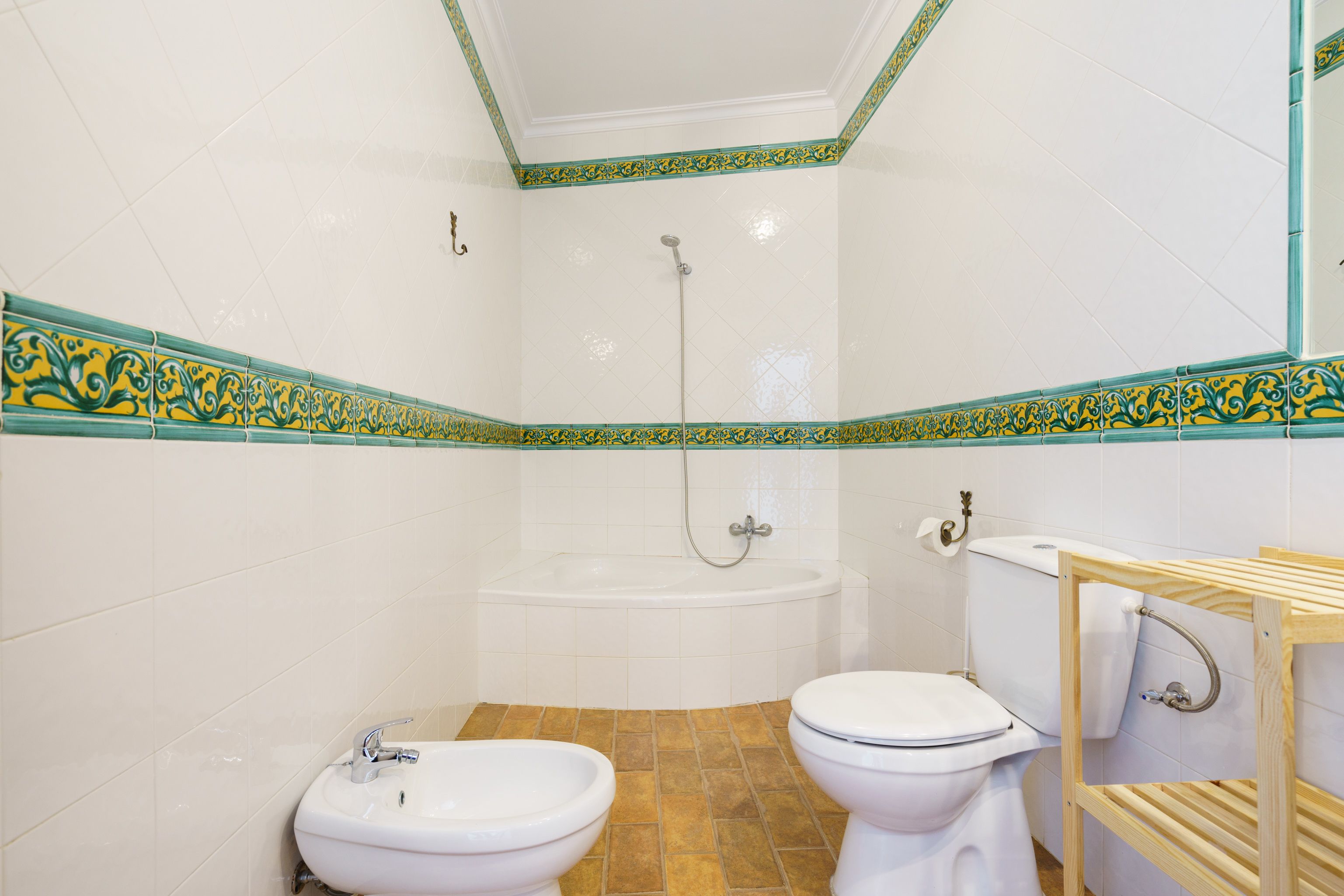 A bathroom with a bathtub, two toilets, and a sink.