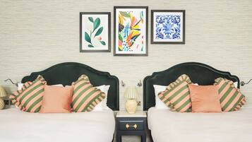 Ein Doppelbett mit gestreiften Kissen, ein Nachttisch mit Lampe und drei gerahmte Kunstwerke an der Wand.