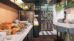 Zona de bufé con diferentes opciones de comida, una recepción y un mostrador de salida.