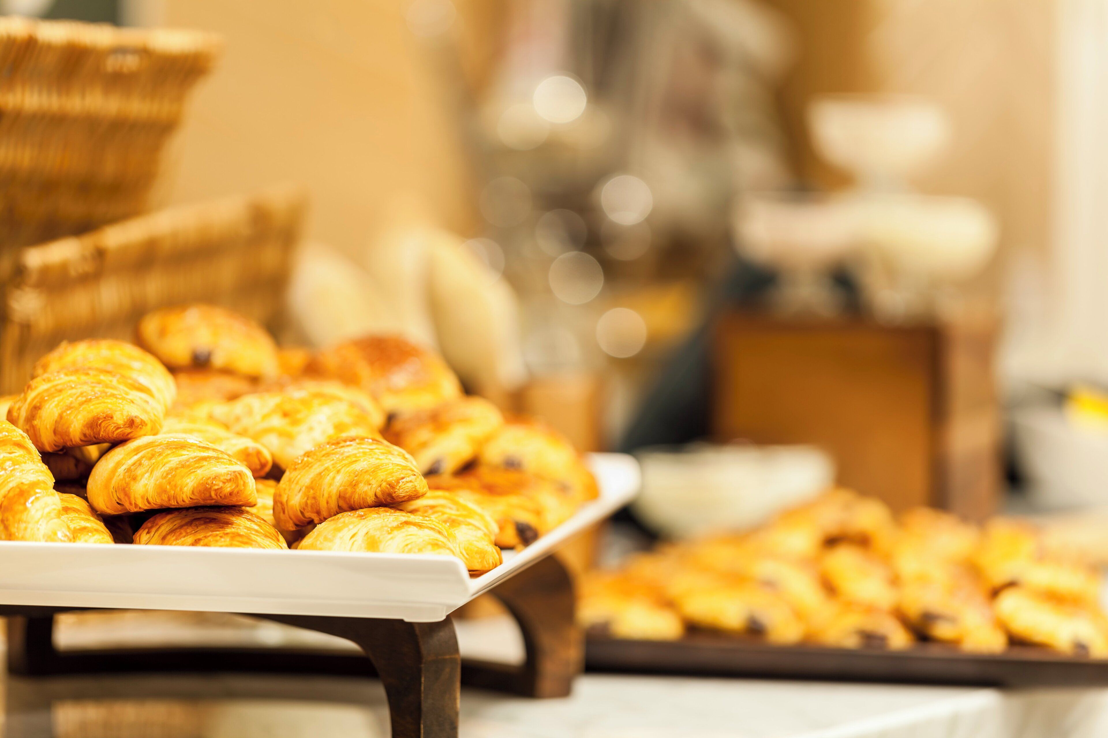 A tray of golden-brown pastries, likely croissants, arranged on a white serving board.