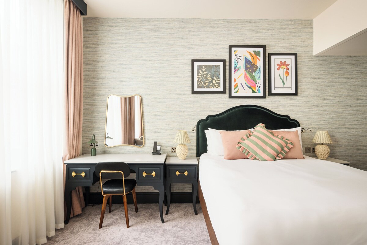 Une chambre d’hôtel avec un lit, un bureau, une chaise et une œuvre d’art au mur.