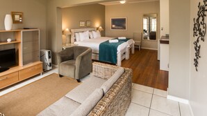Habitación de hotel con cama, sofá, televisión, escritorio y espejo.