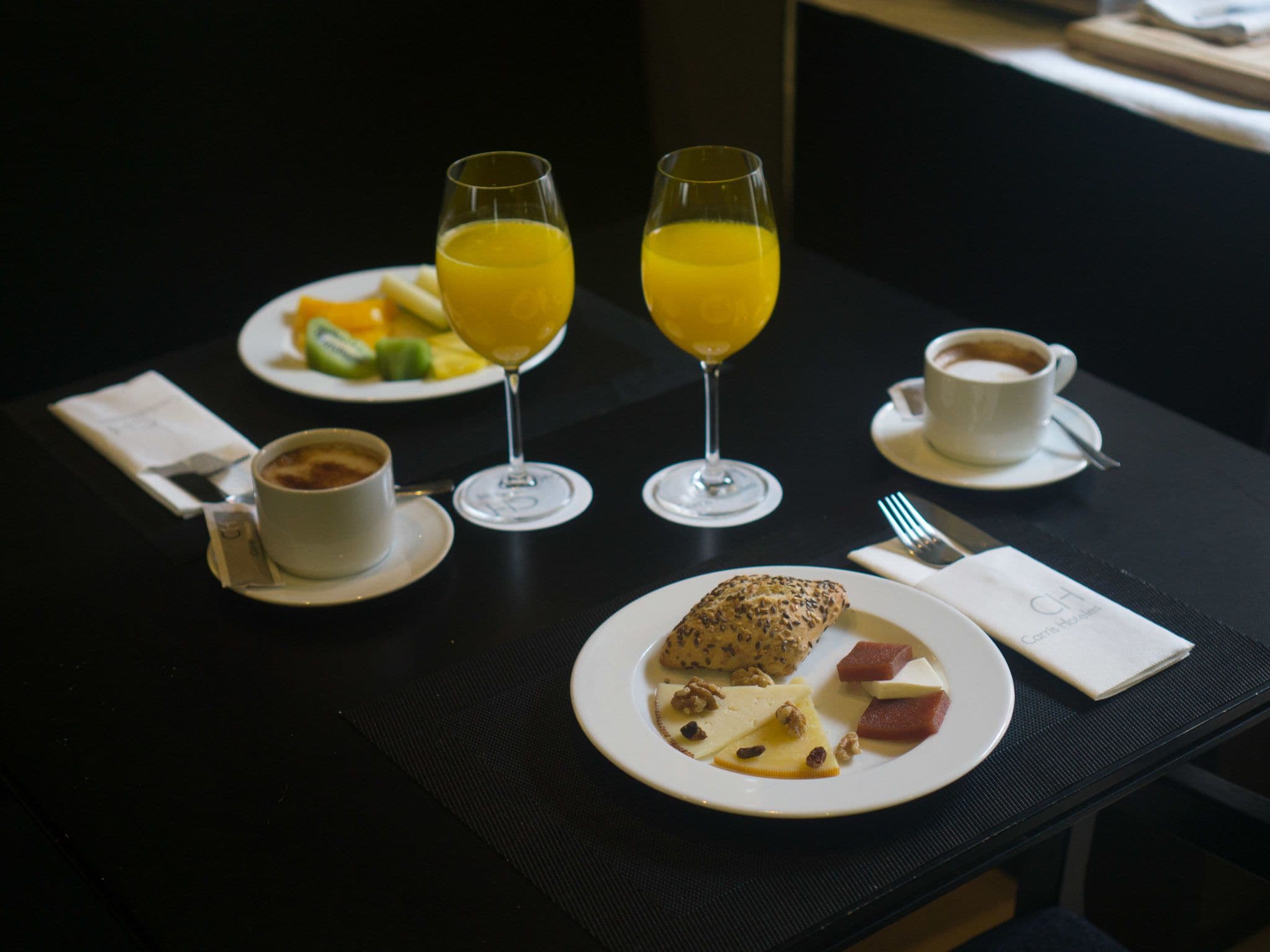 Taula de l'esmorzar amb plats de menjar, dues flautes de suc d'aranja, una tassa de cafè i un croissant.