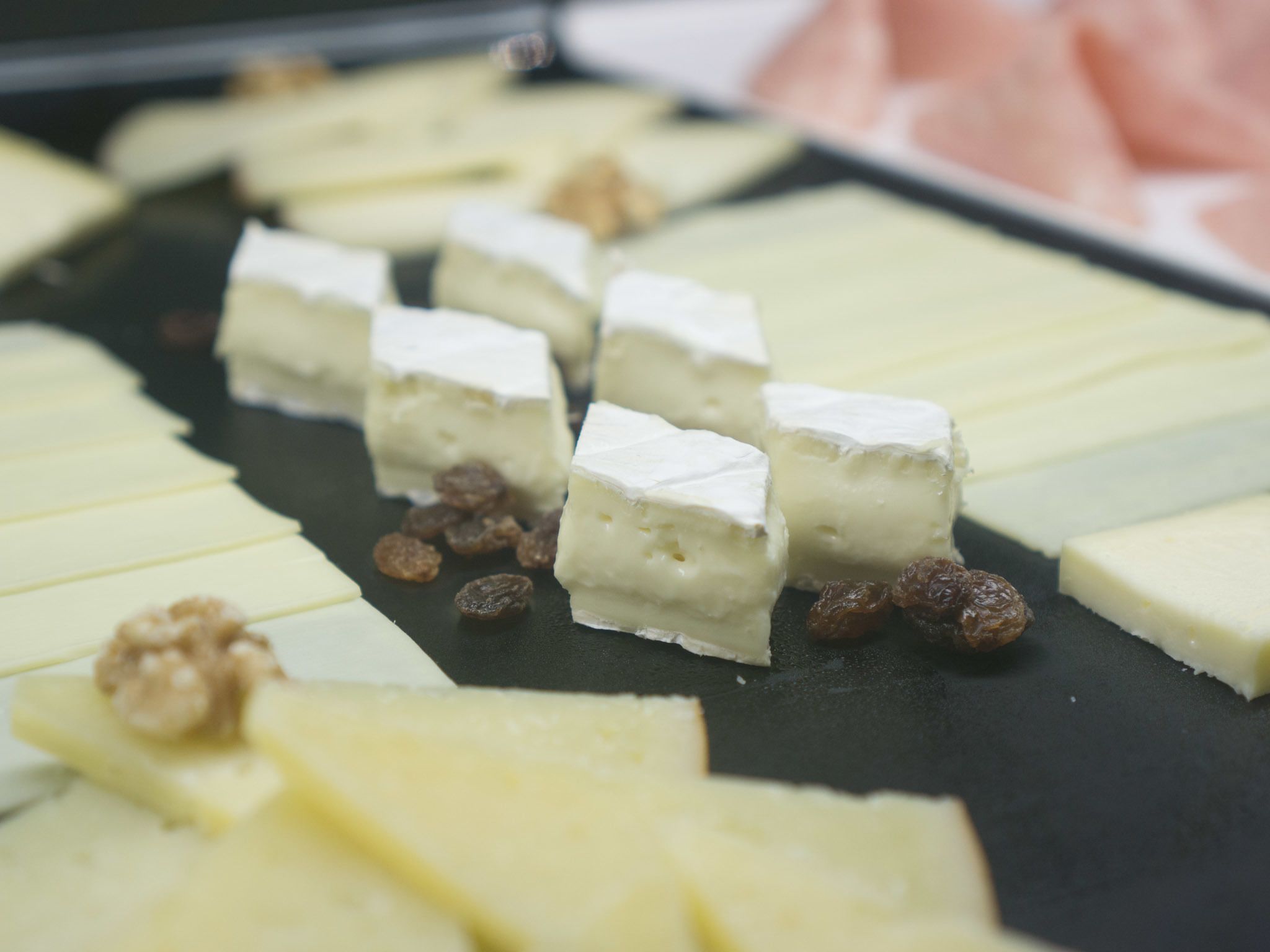 A selection of cheese cubes and raisins on a dark surface.
