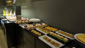A buffet with various food items including pastries, sandwiches, and desserts.