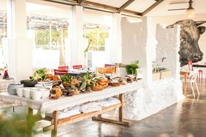 Un bufé de desayuno con diversos alimentos y un mural grande de una vaca en la pared.