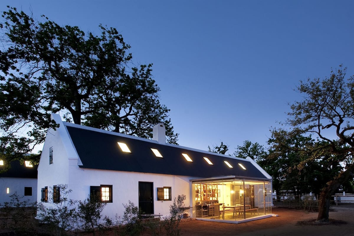 A modern house with a sloped roof and multiple skylights, surrounded by trees.