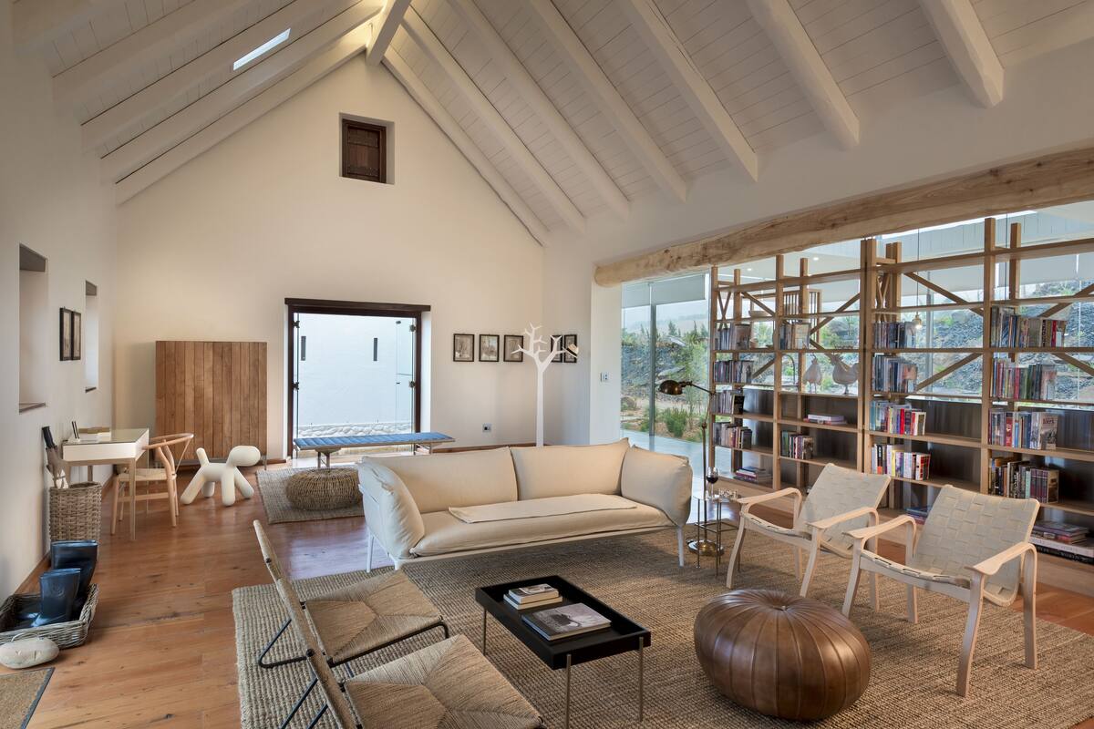 A spacious living room with a high ceiling, a large bookshelf, and a view of the outdoors.