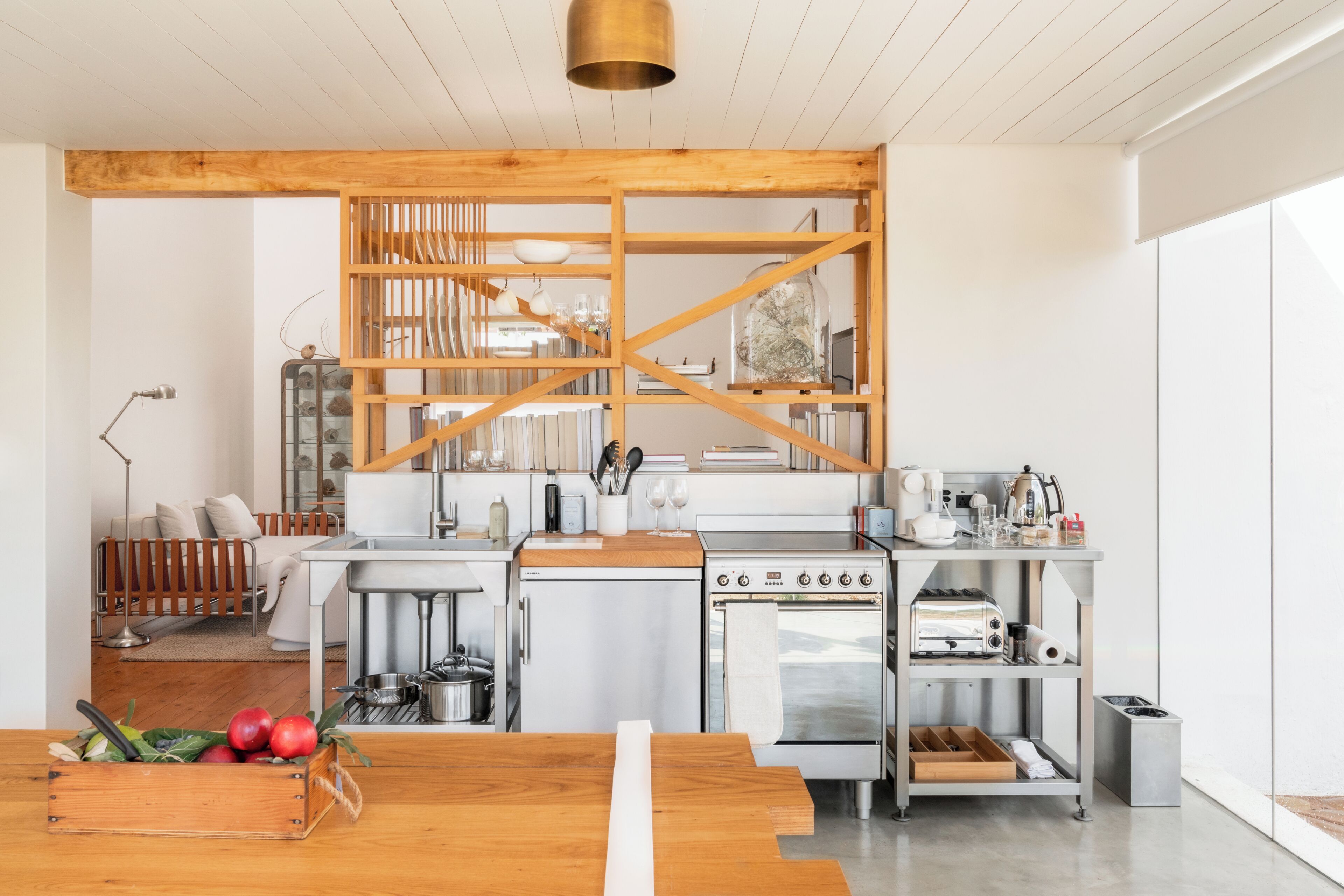 A modern kitchen with wooden beams, stainless steel appliances, and a wooden dining table.