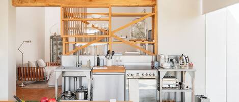 A modern kitchen with wooden beams, stainless steel appliances, and a wooden dining table.