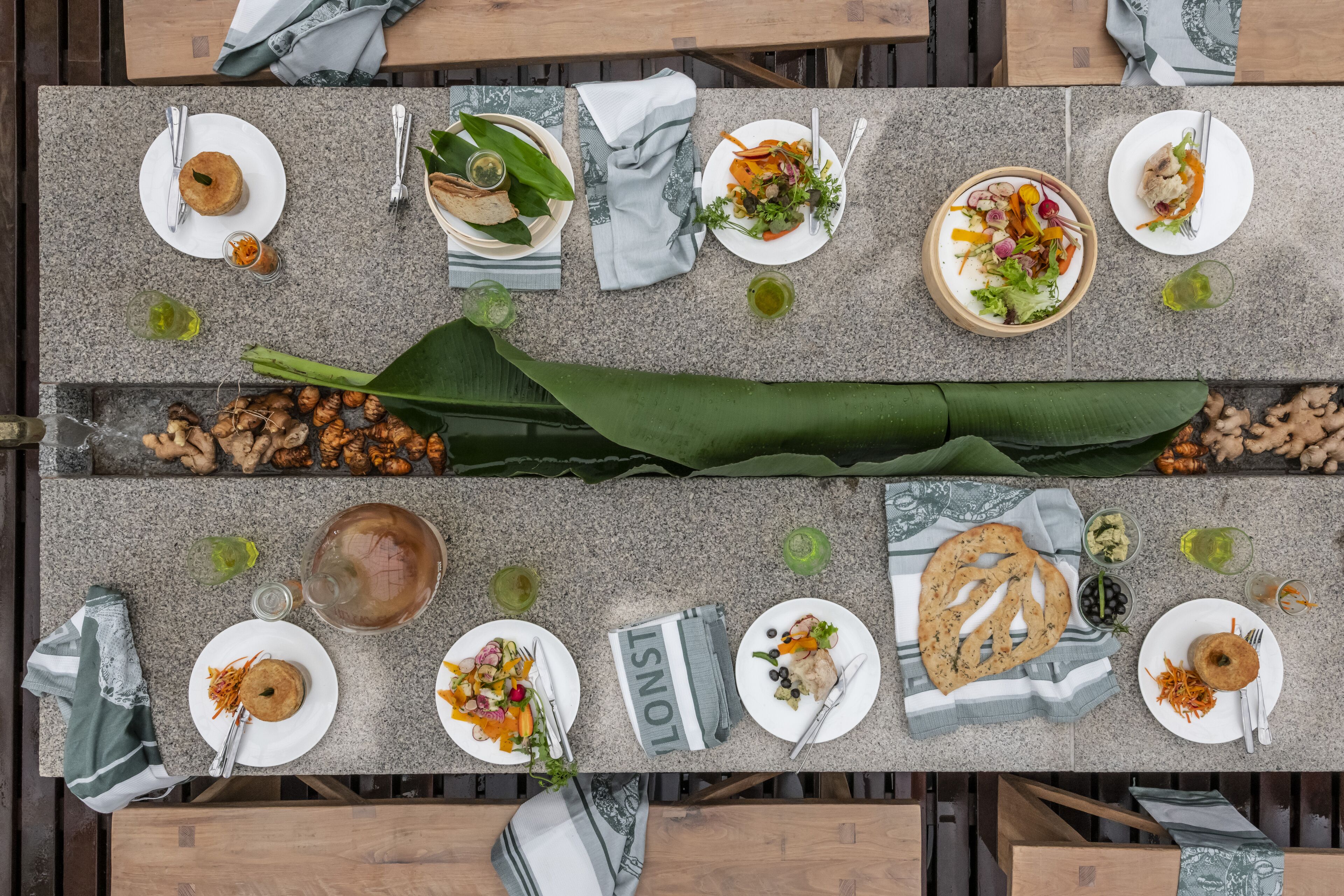 A top-down view of a dining table set with various dishes, including salads, bread, and a drink.