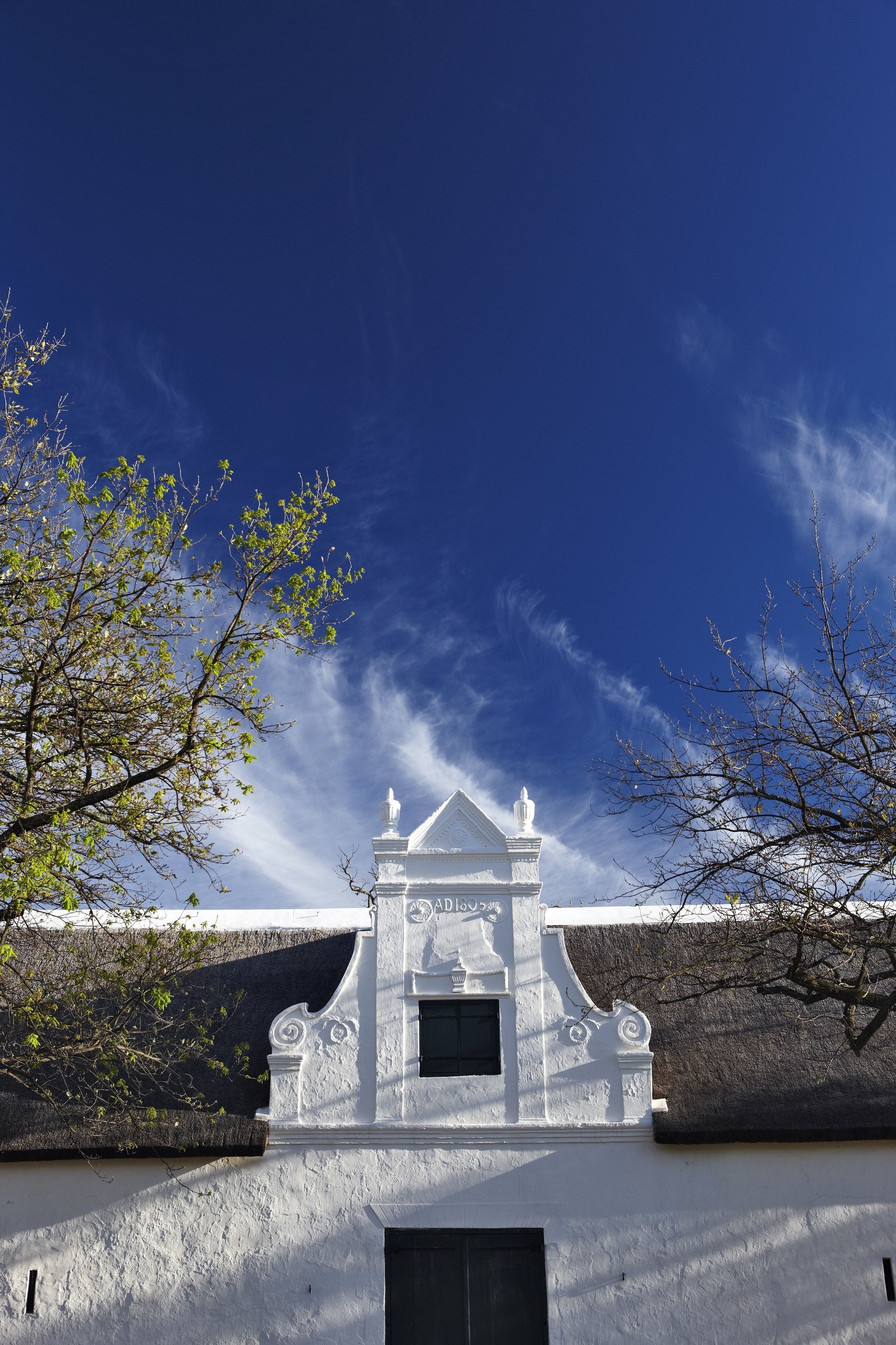 A white building with a small entrance and a statue above it.