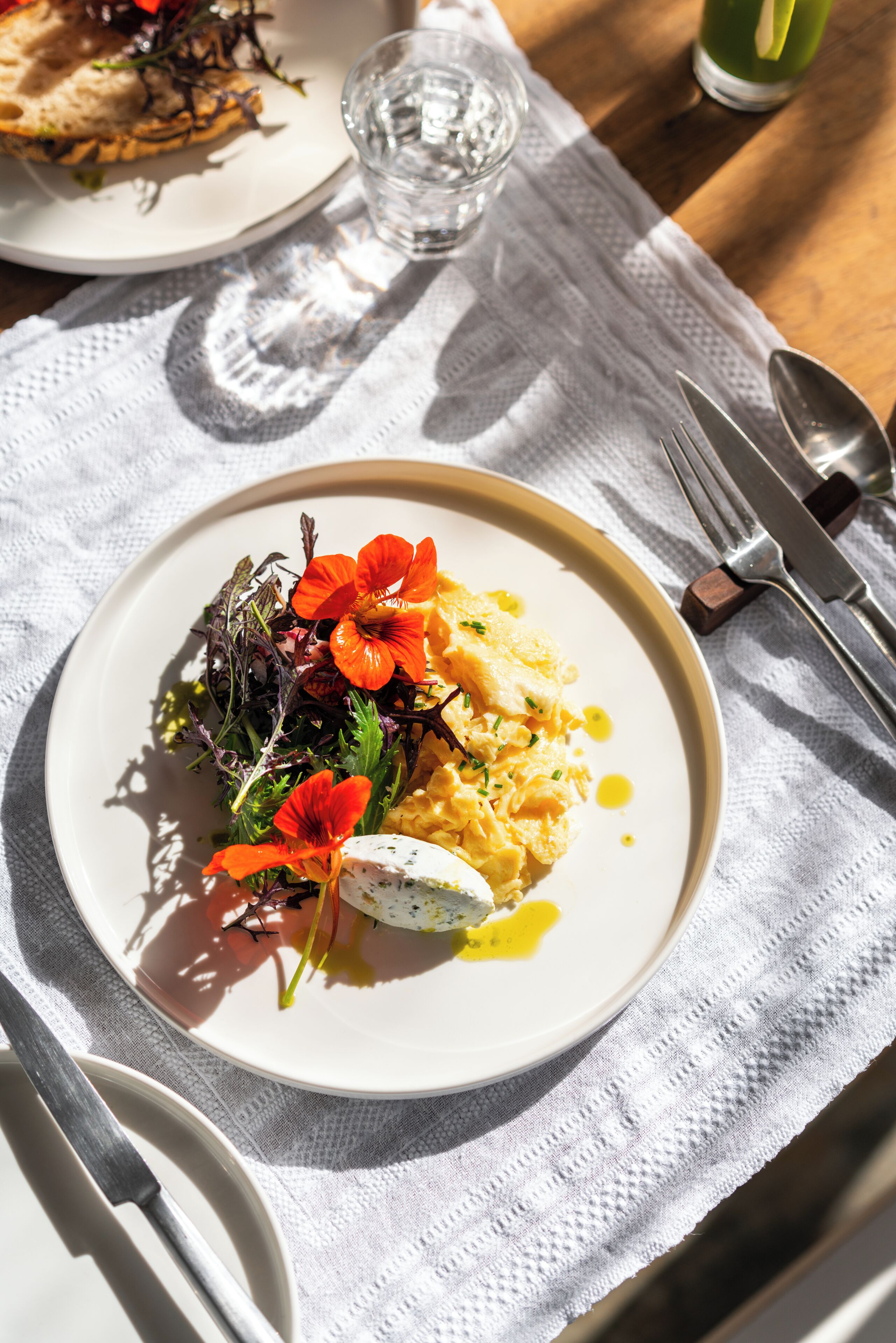 A plate of food with a salad, eggs, and flowers on a white plate.