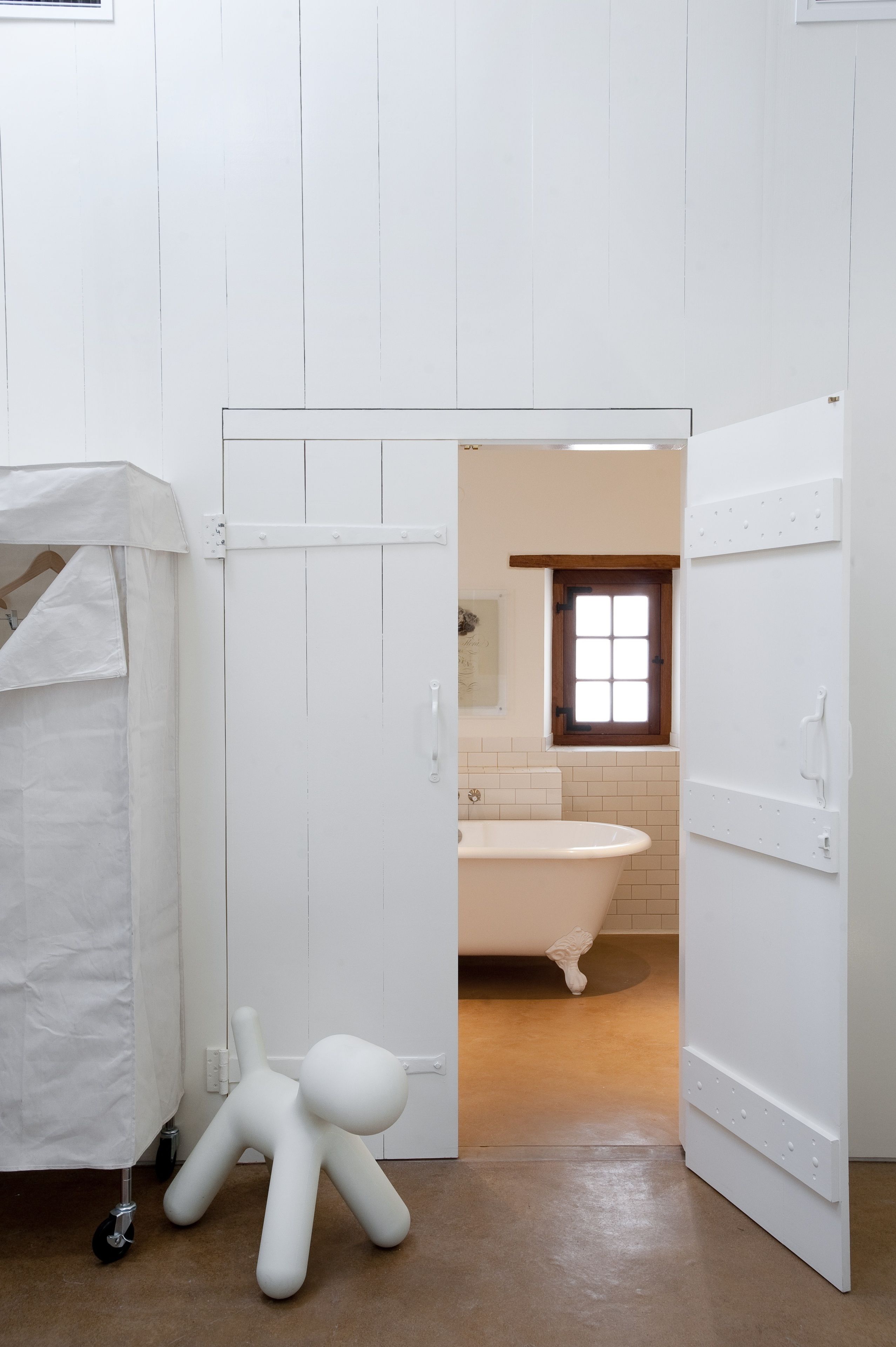 A white bathroom with a bathtub, a white door, and a white floor.
