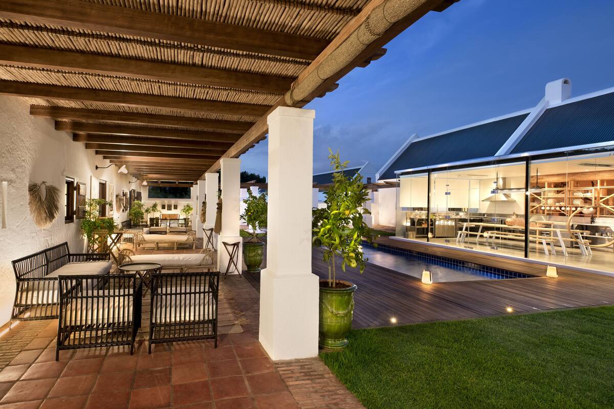 A modern outdoor patio with a pool, wooden deck, and seating area.