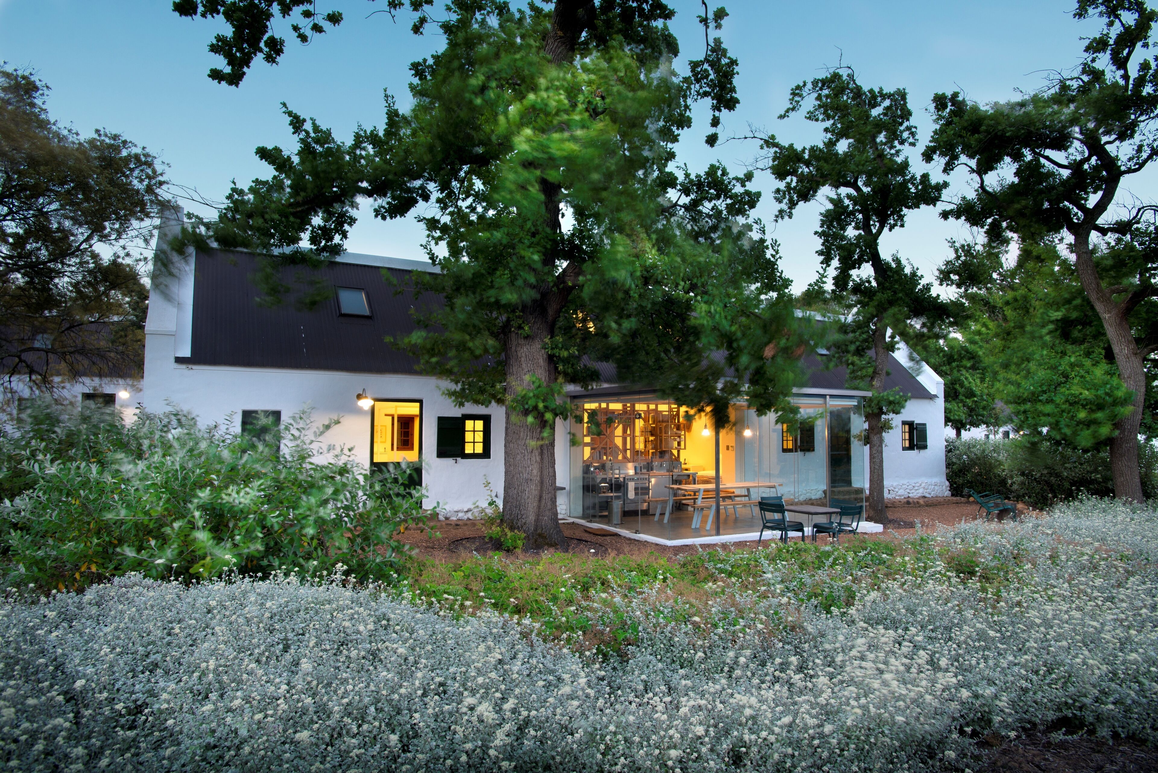 Una casa moderna con un patio, rodeada de árboles y un jardín.