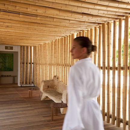 A spa area with a wooden floor, a stone bench, and a bamboo wall.