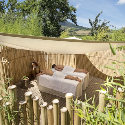 A wooden deck with a bamboo fence, a massage table, and a small planter.