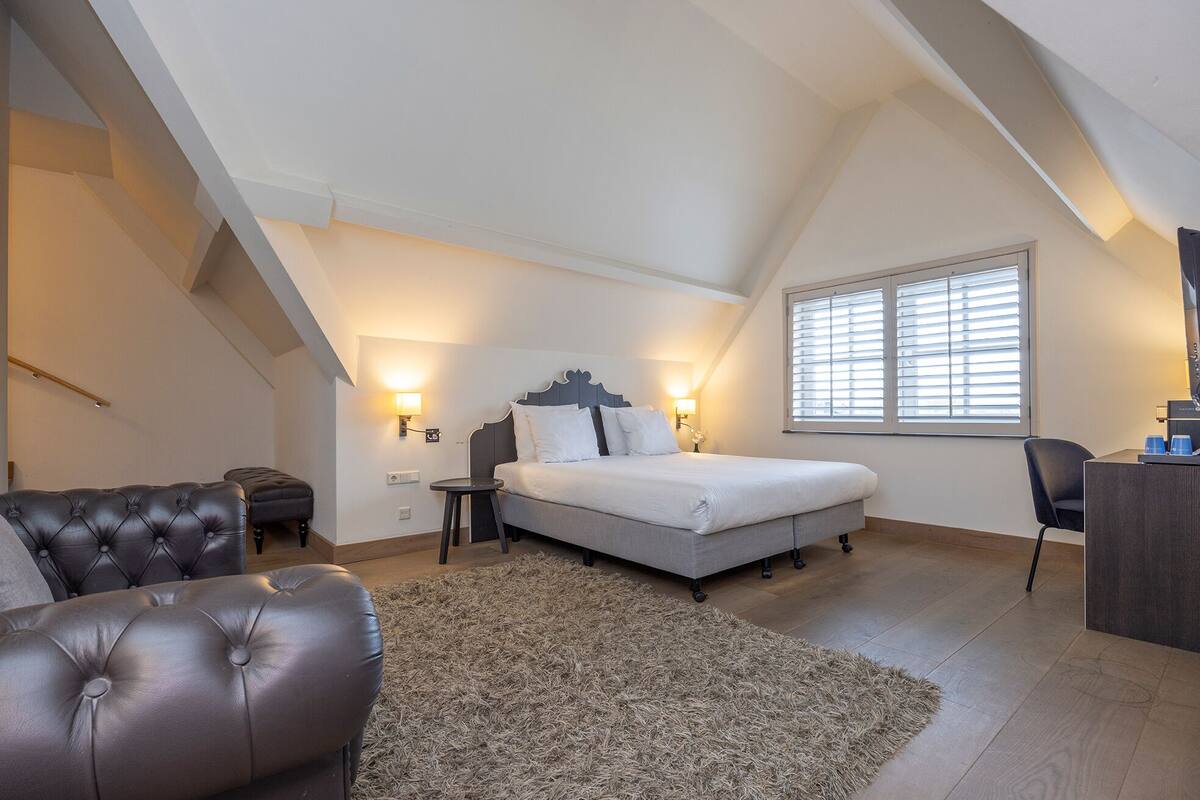 A bedroom with a bed, two bedside tables, a desk, and a chair.