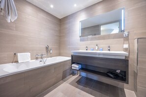 A modern bathroom with a large bathtub, a vanity with a mirror, and a towel rack. - Fletcher Nautisch Kwartier (Huizen)