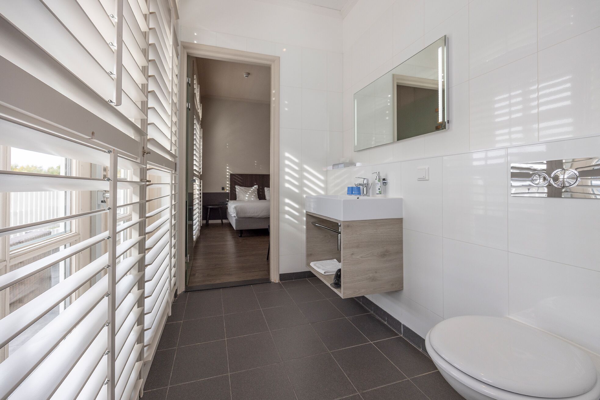 A modern bathroom with a toilet, sink, and mirror.