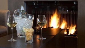 A modern fireplace with a glass top table in front, holding wine glasses and a bottle. - Fletcher Nautisch Kwartier (Huizen)